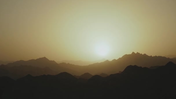 Increíble puesta de sol en las montañas del desierto de Egipto. Las luces del sol bajo el horizonte iluminan el cielo sobre la silueta de las montañas, 4k — Vídeo de stock