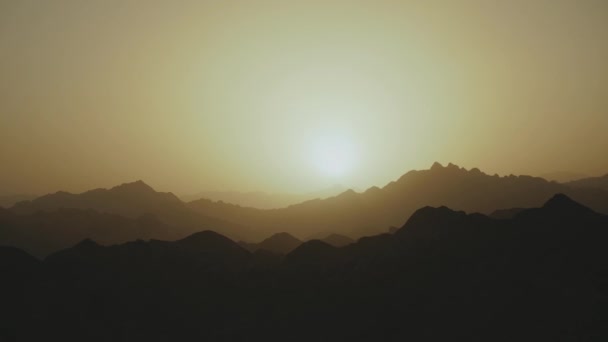Niesamowity zachód słońca w górach pustyni Egipt. Światła słońca pod horyzontem oświetlają niebo nad sylwetką gór, 4k — Wideo stockowe