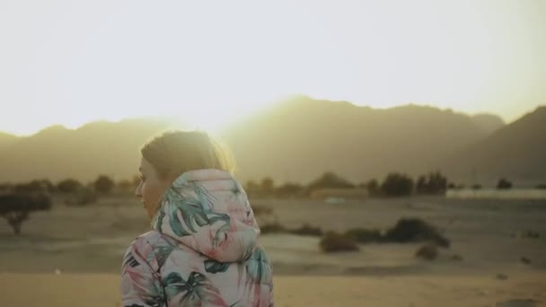 Mulher loira bonita andar ao pôr do sol no deserto. Feminino atravessando o deserto, dunas, close-up, câmera lenta, 4k — Vídeo de Stock