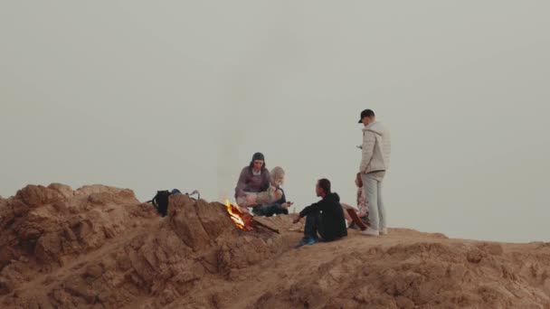 Gruppo di persone che si rilassano sulla cima di una montagna al tramonto, seduti vicino al falò, godendo il loro tempo amicizia, gioventù, 4k — Video Stock