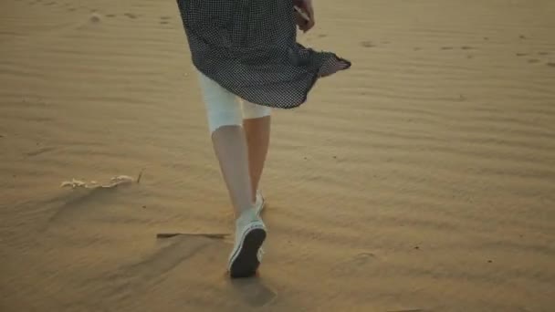 Mulher loira bonita andar ao pôr do sol no deserto. Feminino atravessando o deserto, dunas, close-up, câmera lenta, 4k — Vídeo de Stock