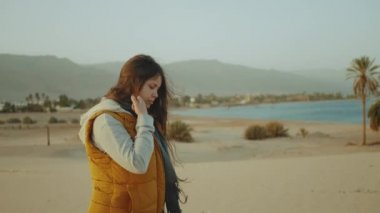 Kadınlar sahilde yürürler ve Horizon 'a bakarlar. Dişinin arkasından kumsal ve mavi deniz manzarası, 4K
