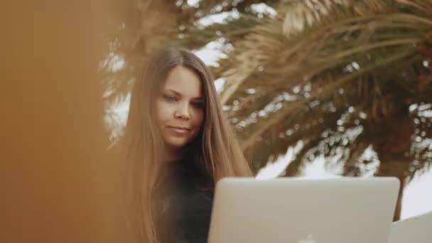 Krásná žena student nebo na volné noze pracující na notebooku, žena sedí na balkóně s horní pohled na dlaň a moře, 4k — Stock video