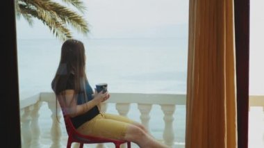 Sabahları balkonda tek başına kahve ya da çay içen, mavi deniz manzaralı, pencereden bakan, Mısır, 4k