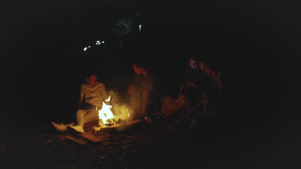 Група друзів розважаються біля багаття на пляжі біля моря вночі, 4k — стокове відео