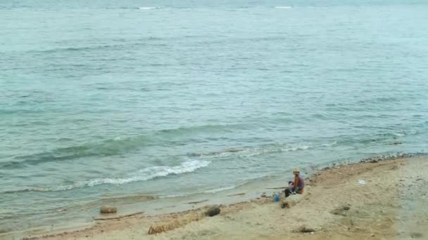 Mère avec un petit bébé dans ses mains assis sur la plage et profiter de la vue sur la mer avec des vagues claires, 4k — Video