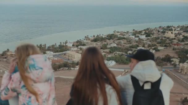 Grupa przyjaciół relaksujących się na szczycie góry na zachodzie słońca i cieszących się widokiem na morze - przyjaźń, młodzież, 4k — Wideo stockowe
