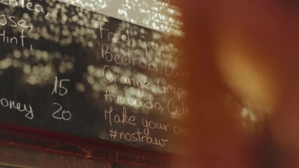 Rückansicht der Kundin Blick auf die Speisekarte an der Wand im vegetarischen Geschäft wählen Sie Getränke, frische Säfte in der Speisekarte in Dahab Shop, Ägypten, 4k — Stockvideo