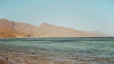 Kızıl denizde şnorkelle yüzen adam, güzel mavi deniz manzarası ve berrak gökyüzü, denizdeki dalgalar ve ufuktaki dağlar, Mısır, Dahab, 4k