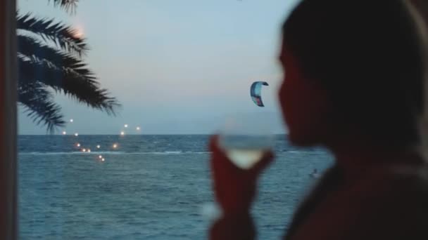 Žena pít víno a podívejte se, jak lidé Draci surfování v krásné čisté vodě v Dahab Egypt. Prozkoumávání modrého moře s horami v pozadí a lidé kite surfing, 4k — Stock video