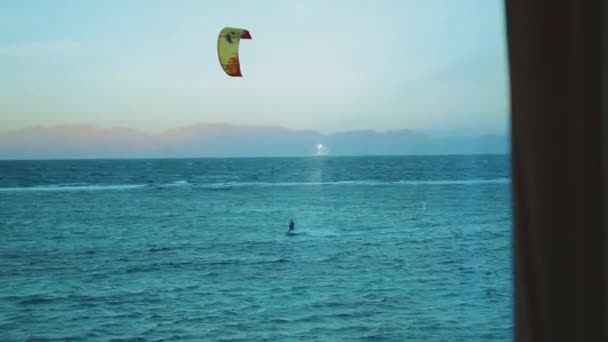 Menschen Kitesurfen in schönen klaren Wasser in Dahab Ägypten Sicht aus dem Fenster. Erkunden des blauen Meeres mit Bergen im Hintergrund und Menschen Kite-Surfen, 4k — Stockvideo
