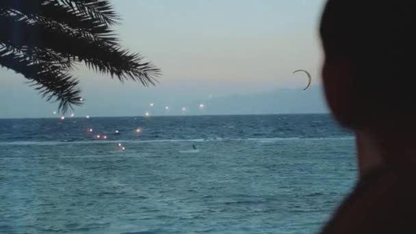 Mulher beber vinho e veja como as pessoas Kite surf em água limpa bonita em Dahab Egito. Explorando o mar azul com montanhas no fundo e pessoas kite surf, 4k — Vídeo de Stock