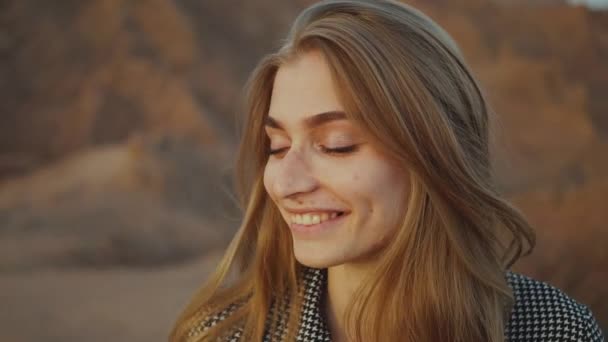 Retrato de una hermosa mujer rubia con los ojos cerrados al atardecer. Feliz joven mujer de pie en una montaña del desierto, paisaje puesta de sol, hd completo — Vídeos de Stock