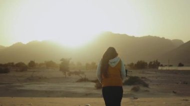 Kadınlar sahilde yürürler ve Horizon 'a bakarlar. Kumsal manzarası ve mavi deniz, dişinin sırtından, tam kapasite.