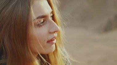 Yakın plan kadın gitar çalıyor ve çölde şarkı söylüyor gün batımında manzara, çöl dağlarında arka plan, tam teçhizat