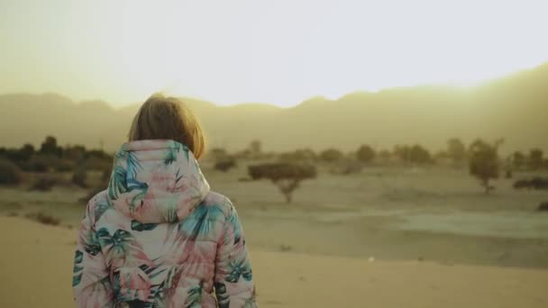 Güzel sarışın kadın çölde gün batımında yürüyor. Çölde giden bir kadın, kum tepeleri, yakın plan, tam teçhizat — Stok video