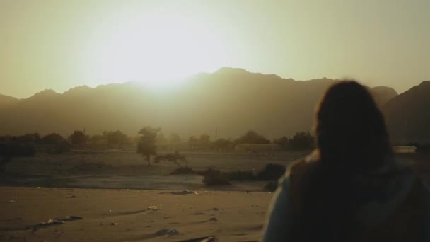 Silhouette einer schönen jungen Frau beim Sonnenuntergang in der Wüste. Weibchen gehen durch die Wüste, Dünen, Wind weht, voll hd — Stockvideo