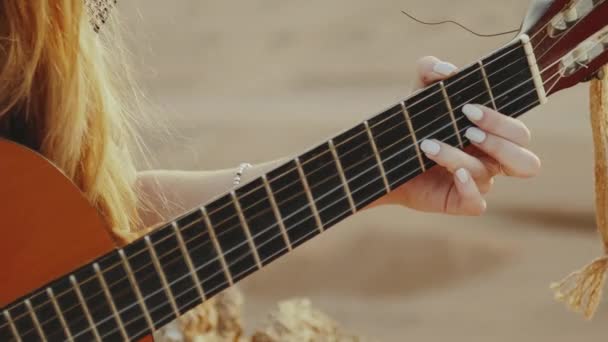 Close-up vrouw spelen gitaar en zingen in de woestijn in zonsondergang landschappen, woestijn bergen achtergrond, full hd — Stockvideo