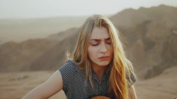 Mulher tocando guitarra e cantando no deserto em paisagens do pôr do sol, deserto montanhas fundo, hd completo — Vídeo de Stock