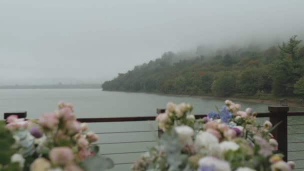 Bruiloft bloemboog en decoratie meer en bergen in mist op de achtergrond, close - up bruiloft boog met roze bloemstuk, slow motion, full hd — Stockvideo