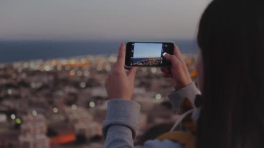 Akşamları kadın akıllı telefondan denizin fotoğrafını çeker. Kadın dağın tepesinde durur ve Horizon 'a bakar.