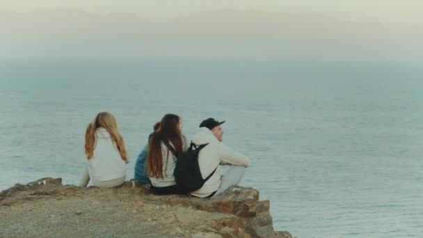 Gruppo di turisti che si rilassano sulla cima di una montagna al tramonto e godono della vista sul mare amicizia, gioventù, hd completo — Video Stock