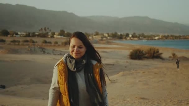 Uzun saçlı bir kadın çölde yürüyor, arka planda deniz ve dağlar, Mısır, tam yol. — Stok video