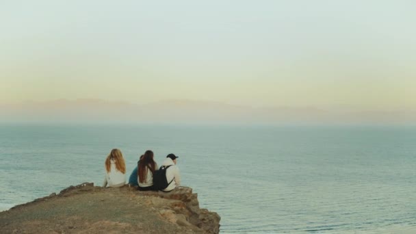 Gruppo di turisti che si rilassano sulla cima di una montagna al tramonto e godono della vista sul mare amicizia, gioventù, hd completo — Video Stock