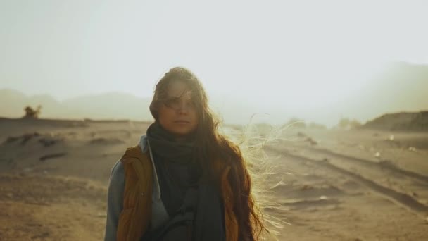 Portret van een mooie vrouw bij zonsondergang in woestijnbergen aan de horizon. Gelukkige jonge vrouw staande in de wind tegen Egypte woestijn zonsondergang landschap, full hd — Stockvideo