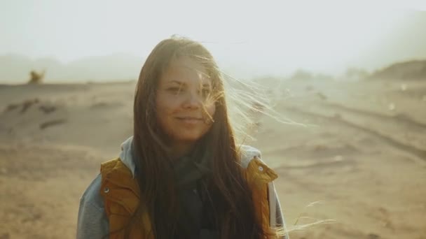 Csinos nő portréja naplementekor a láthatáron lévő sivatagi hegyekben. Boldog fiatal nő áll a szél ellen Egyiptom sivatagi naplemente táj, teljes HD — Stock videók