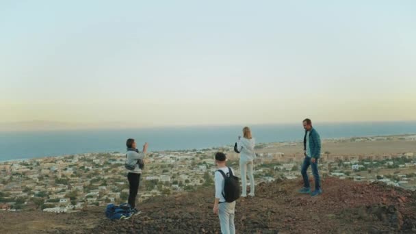 Gruppo di turisti che si rilassano sulla cima di una montagna al tramonto e godono della vista sul mare amicizia, gioventù, hd completo — Video Stock