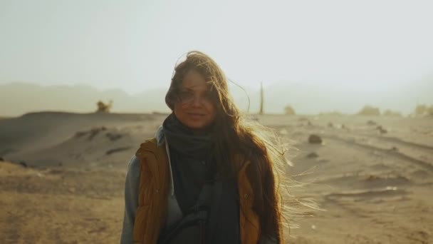 Retrato de una mujer bonita al atardecer en las montañas del desierto en el horizonte. Feliz joven mujer de pie en el viento contra Egipto desierto puesta del sol paisaje, full hd — Vídeos de Stock