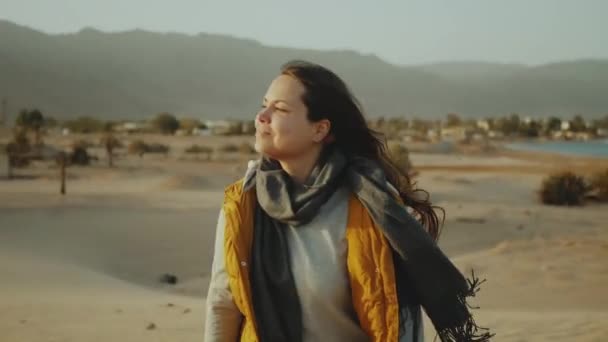 Donna con i capelli lunghi passeggiata nel deserto, mare e montagne sullo sfondo, Egitto, hd completo — Video Stock