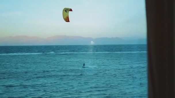 Samotny człowiek kitesurfing w czerwonym morzu o zachodzie słońca, Dahab Egipt, punkt widzenia z okna. Ludzie windsurfing i kitesurfing, pełne hd — Wideo stockowe