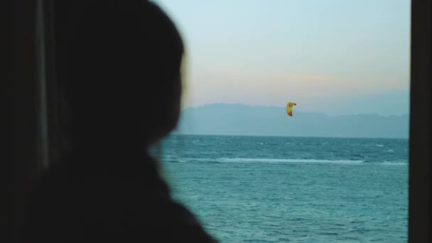 Mujer mira cómo la gente Kite surf en la noche en Egipto mar rojo. Punto de vista desde la ventana, hd completa — Vídeos de Stock