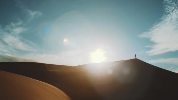 Один чоловік стоїть у пустелі Сахара на горизонті, золотий пісок і хмарне небо. Пісок підкорив Аравійську пустелю. Піщані дюни хвилястий візерунок. Природа, Марокко, 4k — стокове відео