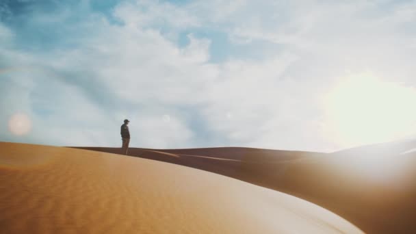 Alone man standing in Sahara desert on horizon, golden sand and cloudy sky. Sand dunes Arabian desert. Sand dunes wave pattern. Nature background, Morocco, 4k — Stock Video