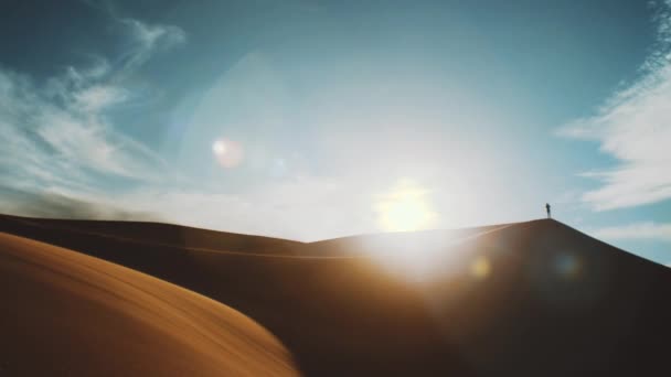 Samotný muž stojící v saharské poušti na obzoru, se zlatým pískem a zamračenou oblohou. Písečné duny Arabská poušť. Vzorec písečných dun. Přírodní zázemí, Maroko, 4k — Stock video