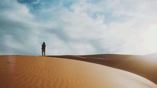 Seul homme prenant selfie dans le désert du Sahara à l'horizon, sable doré et ciel nuageux. Dunes de sable désert arabe. Modèle d'onde des dunes de sable. Nature, Maroc, 4k
