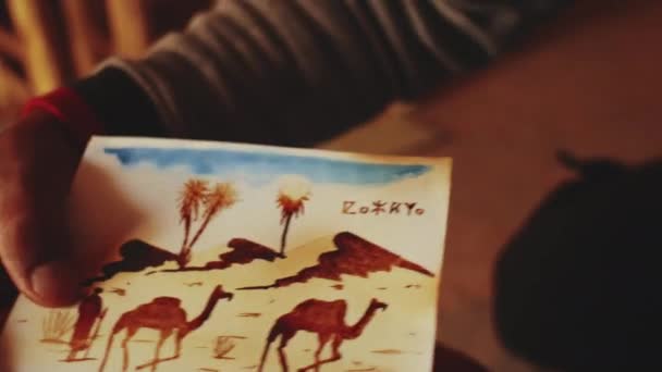 Марокканська людина виготовляє поштові листівки для туристів древньої фортеці Айт Бен Хадду, бербер, Марокко поблизу Уарзазазате в Атлаських горах, 4k. — стокове відео
