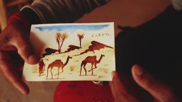 Марокканська людина виготовляє поштові листівки для туристів древньої фортеці Айт Бен Хадду, бербер, Марокко поблизу Уарзазазате в Атлаських горах, 4k. — стокове відео