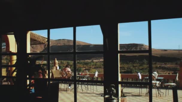 Kvinna har traditionell frukost på terrassen i marockanska riad med vackra öken stenar utsikt, synvinkel från fönstret, 4k — Stockvideo