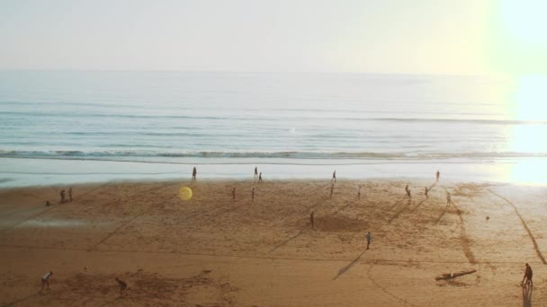 Giovani uomini che giocano a calcio sulla spiaggia al tramonto, silhouette di persone sulla spiaggia dell'oceano Atlantico, Taghazout costa, Marocco, 4k — Video Stock