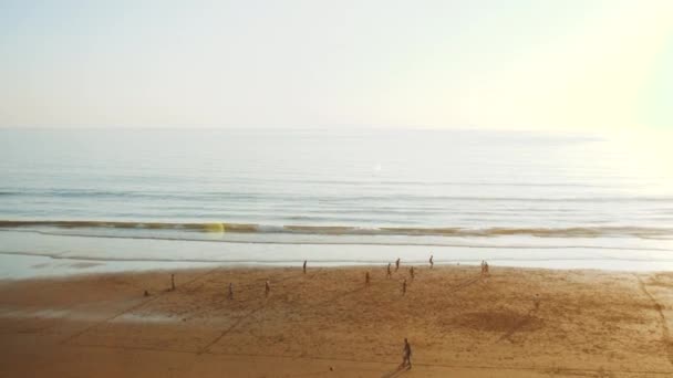 Młodzi mężczyźni grający w piłkę nożną na plaży o zachodzie słońca, sylwetka ludzi na plaży Oceanu Atlantyckiego, wybrzeże Taghazout, Maroko, 4k — Wideo stockowe