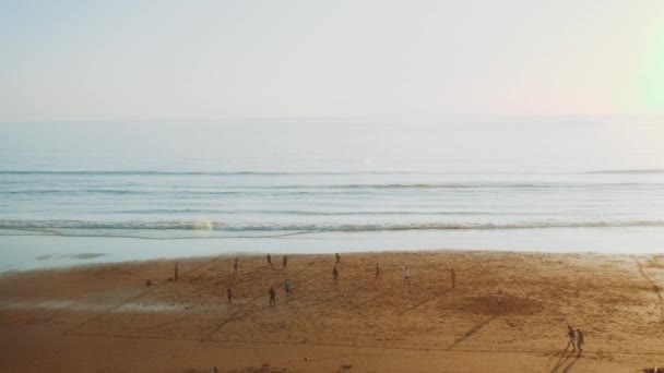 Jovens Jogando futebol na praia ao pôr do sol, Silhueta de pessoas na praia do oceano Atlântico, Taghazout litoral, Marrocos, hd completo — Vídeo de Stock