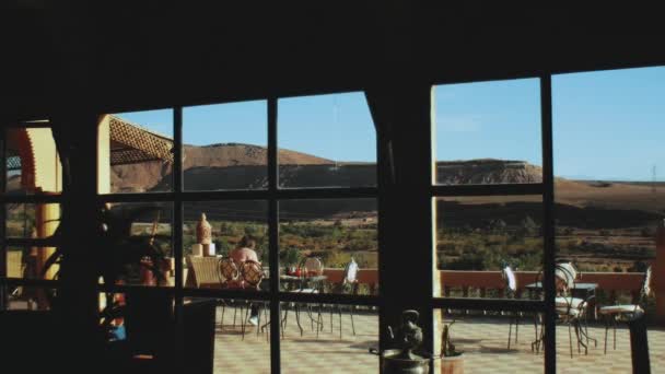 Mulher tem café da manhã tradicional no terraço do riad marroquino com bela vista rochas do deserto, ponto de vista da janela, hd completo — Vídeo de Stock