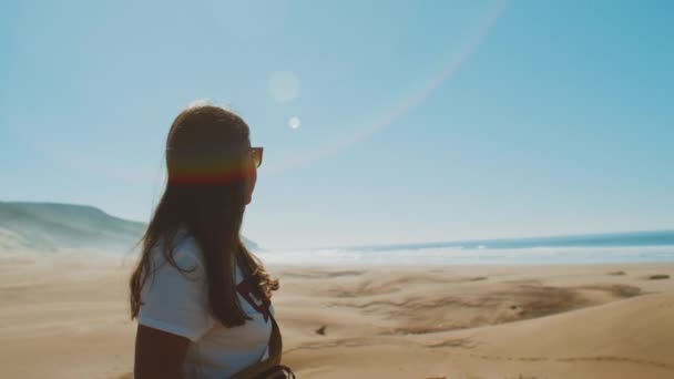 Las mujeres con gafas de sol miran al horizonte oceánico. Mujer en no enfoque, Increíbles dunas de arena por el hermoso océano azul, Dahkla, Marruecos, conejitos de sol en la cámara, hd completo — Vídeo de stock