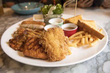 Kızarmış balık, domuz eti ve yemek ve ekmek soslu sosis ızgara biftek salata çizgi ile servis edilir