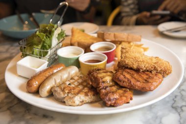 Kızarmış balık, domuz eti ve yemek ve ekmek soslu sosis ızgara biftek salata çizgi ile servis edilir