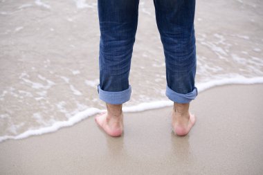 Genç adam denizde sabah ayakta